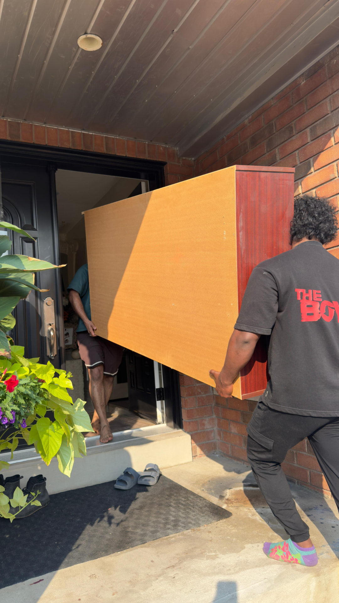 Acemovers movers carrying a large wooden cabinet through a front door